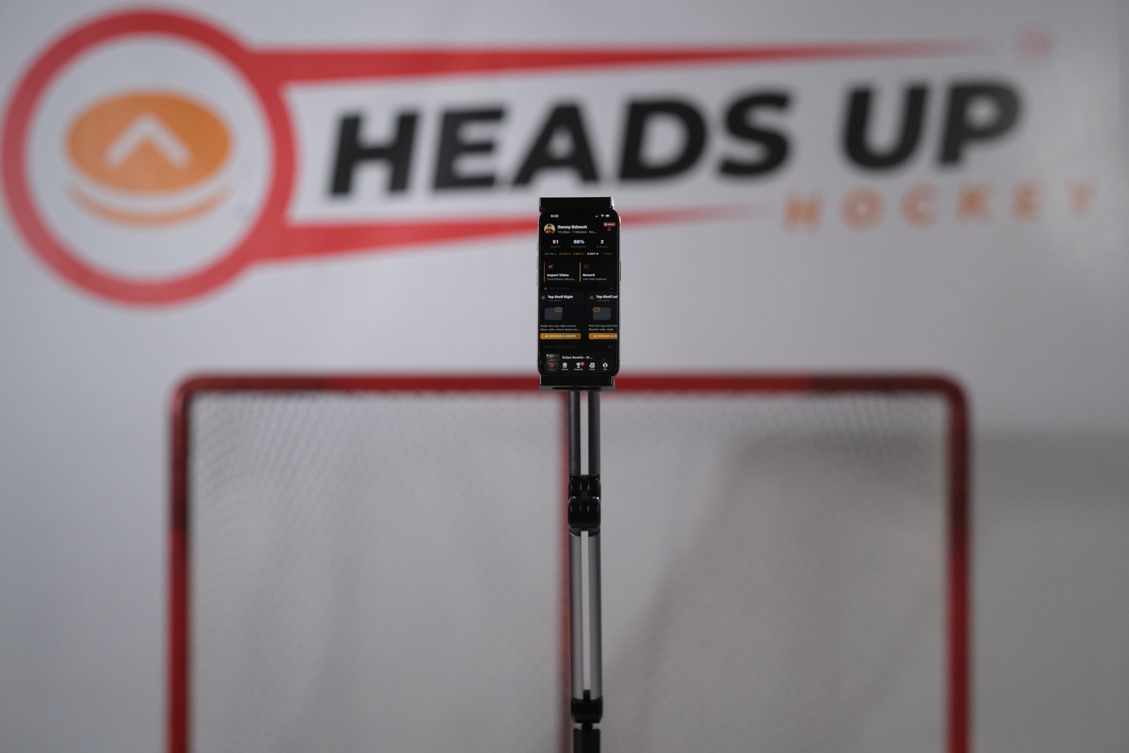 Phone mounted on a stand in front of a hockey net, a modern alternative to traditional shot trainers